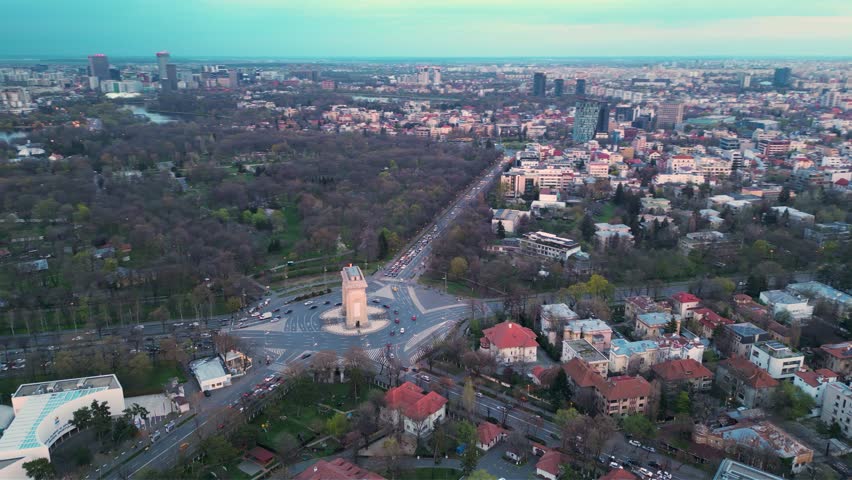 Romania - Aerial footage of the Bucharest Arch of Triumph - Arcul de triumf monument, roundabout, herastrau park and cars driving around. Rotary intersection traffic circle seen from the air. 