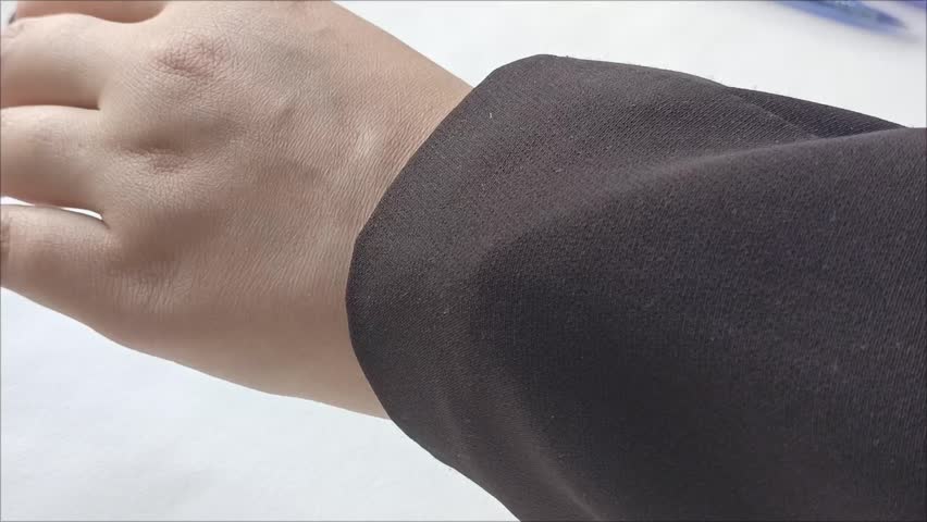 A woman in a black jacket watches the time on a mechanical watch on her hand. The concept of a person waiting for something, running late. Business.