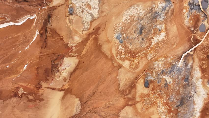 Top-down aerial view of Námafjall geothermal area in Hverarönd, Iceland. Boiling mud pools, sulfur deposits, and vivid mineral patterns form an alien, Mars-like volcanic landscape.