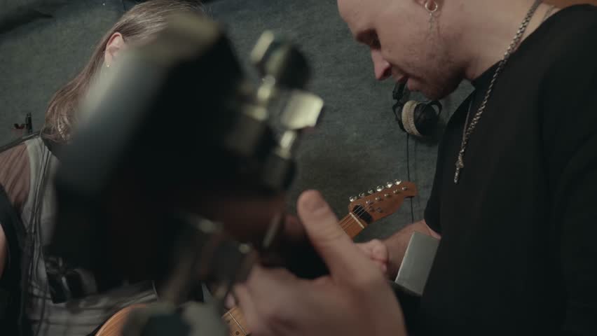 Small indie band of two guitarists rehearses performance in recording studio