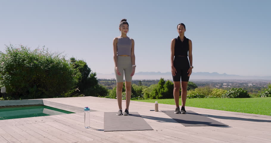 Diverse female friends inhaling raising arms shifting into tree pose on deck yoga mats for balance. Fitness, wellness, mindfulness, serenity, nature, outdoor, harmony