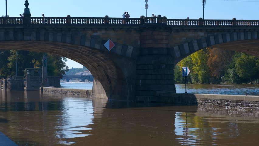 Legion bridge over vltava river in prague. Tourists walking leisurely along legion bridge, capturing scenic panorama of vltava river flowing through historic prague during bright summer afternoon