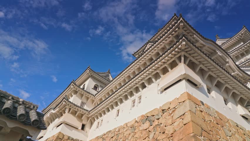 Himeji, Japan - Sep 24 2024, 4k, panoramic view of Himeji Castle, White Heron Castle from behind the roof of the castle outbuildings, in the daytime with blue sky, without people, Himeji, Japan
