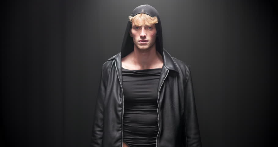Fashion, walking and face of man on runway in designer brand, clothes and outfit at showcase event. Black background, catwalk and portrait of model on stage for couture, trendy collection and style