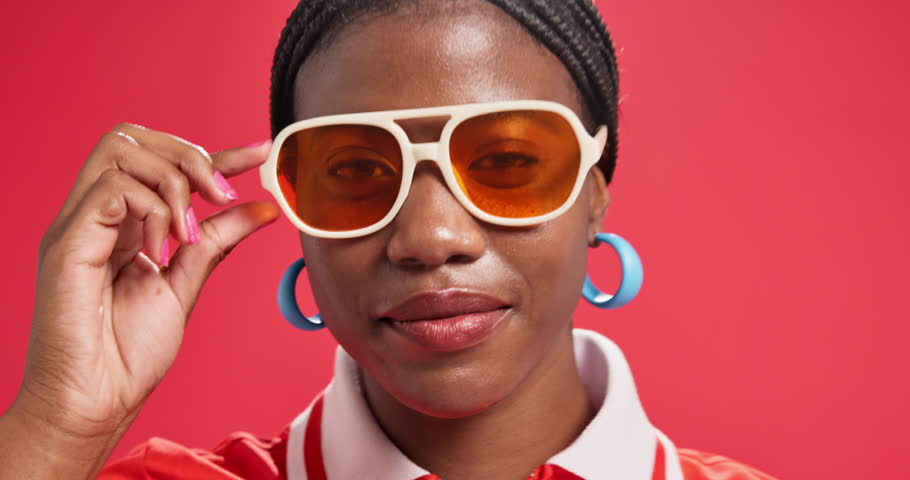 Black woman, sunglasses and wink in studio with face, flirt and secret with fashion by background. African person, girl and happy with laugh for deal, trendy style and joke with closeup in Nigeria