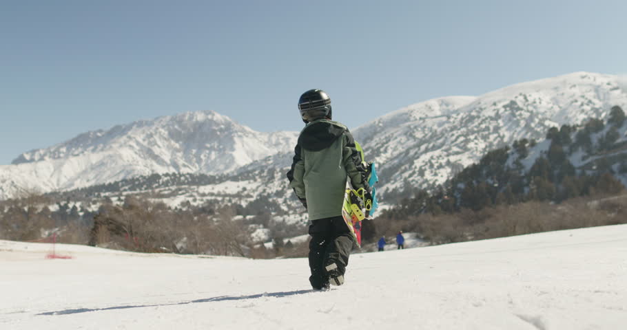 Little Snowboarder Runs Downhill at Ski Resort in Winter