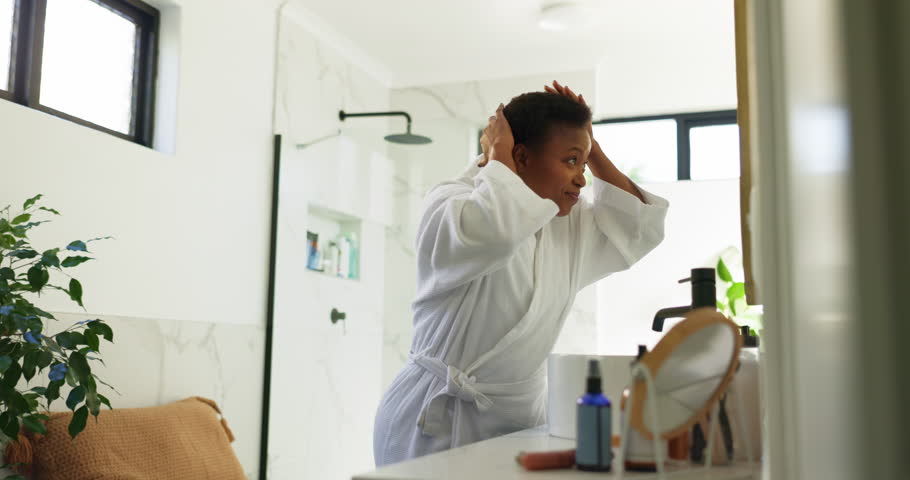 Black woman, bathroom or happy with haircare in mirror for morning routine, getting ready or beauty. Grooming, person and smile in home for afro maintenance, hair growth treatment and daily self care