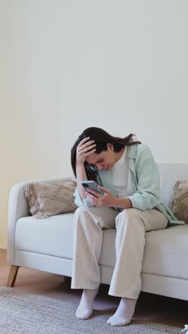 Woman feeling stressed reading bad news on mobile phone