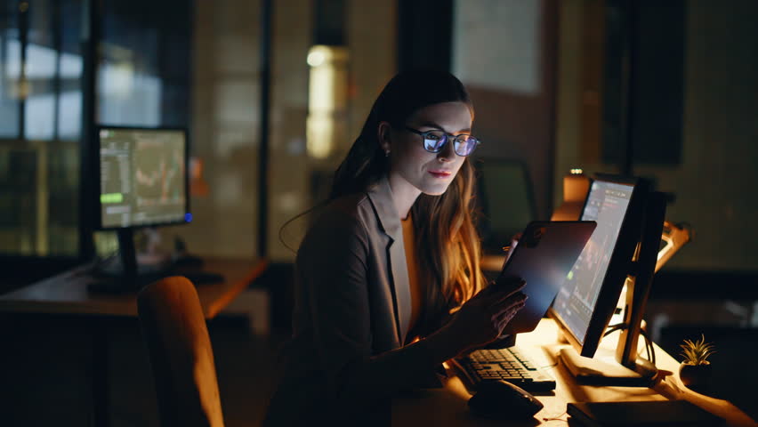 Nighttime investor analyzing blockchain data using touchscreen device in modern workspace closeup. Happy woman focused working at evening hours at home office. Financial trader studying market trends