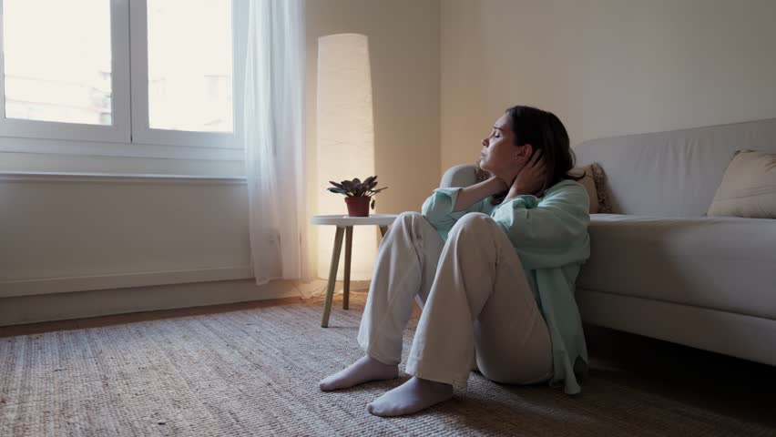 Woman suffering from depression sitting on floor next to sofa