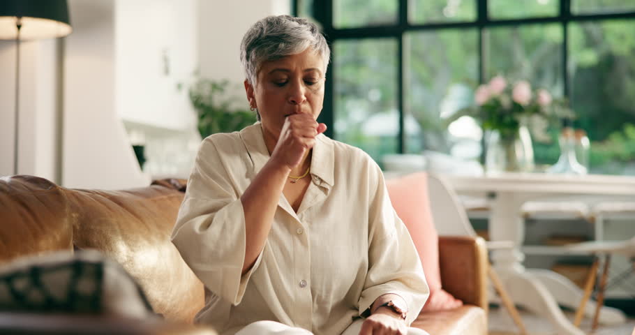 Sick, senior woman and cough in home with chest pain, pneumonia infection and tired breathing. Retirement, old person and sore throat with lung disease, airway inflammation and health issue on sofa