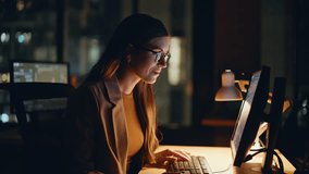 Stock market specialist working computer at night room closeup. Pensive woman using computer looking solution at evening workplace. Smiling broker in glasses feeling thoughtful analyzing diagrams  - Powered by Shutterstock - Get 15% off with code: PIKWIZARD15