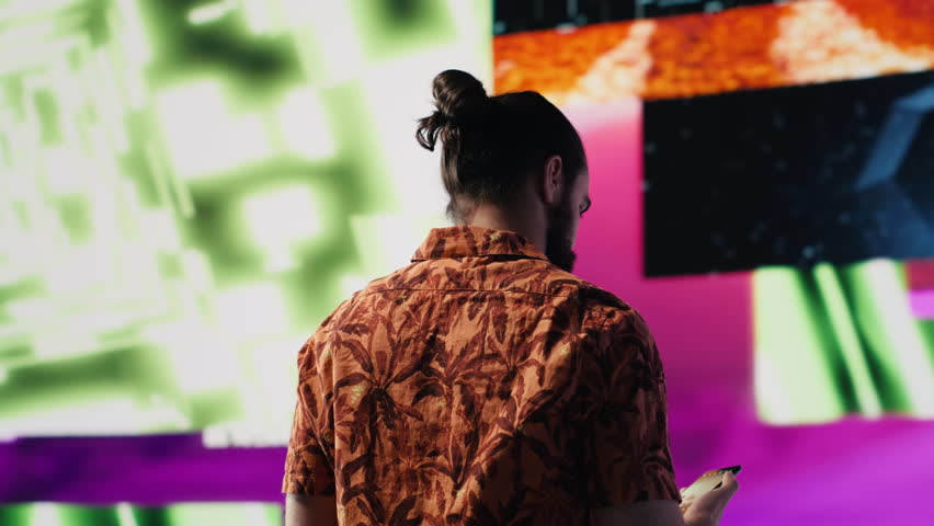 Young carefree man takes selfies and videos surrounded by fun neon lights and beats, representing the fusion of modern DJ culture, media influence and digital art for performance. Camera A.
