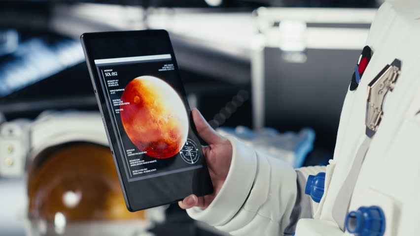 Close up of astronaut using tablet to check Mars telemetry data during human expansion in space mission. Cosmonaut in starship analyzes red planet surface supporting mankind survival, camera B - Powered by Shutterstock - Get 15% off with code: PIKWIZARD15