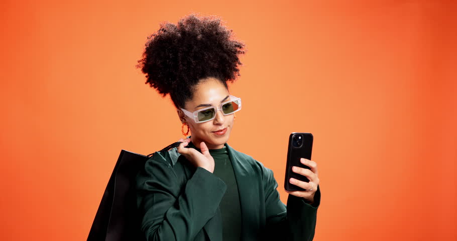 Studio, selfie and woman with shopping bags, smile and stylish with discount for clothes and memory. Orange background, influencer and African person with products for fashion, happy and photography