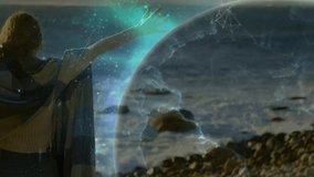 Woman wearing shawl lifting arms on rocky shoreline, generating glowing tech sphere mapping earth. Cosmic, mystical, landscape, ambient, fantasy, spiritual, innovation - Powered by Shutterstock - Get 15% off with code: PIKWIZARD15