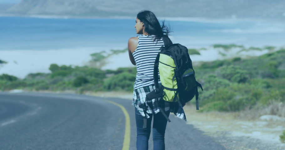 Hiker walking along coastal road revealing 3D globe overlay hitchhiking toward passing vehicles. Adventure, exploration, journey, wilderness, outdoor, travel, scenic