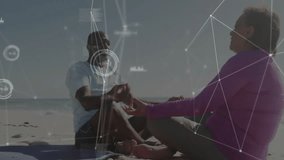 Mature couple meditating on sand holding hands, breathing animating network showing health metrics. Wellness, relaxation, connectivity, mindfulness, serenity, digital, harmony - Powered by Shutterstock - Get 15% off with code: PIKWIZARD15