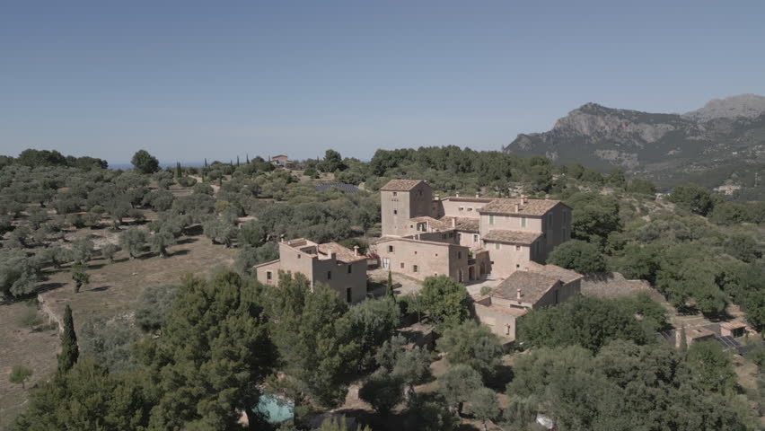 4K drone footage close to Muleta Gran Hotel in Mallorca, revealing a peaceful hilltop retreat surrounded by mountains, olive groves, and sea views—ideal for luxury, travel, and nature visuals.