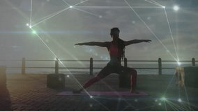 Woman unfurling yoga mat seaside dawn holding warrior II pose as glowing mesh pulsing for wellness. Fitness, meditation, mindfulness, serenity, energy, balance, landscape - Powered by Shutterstock - Get 15% off with code: PIKWIZARD15