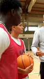 Basketball coach standing near team, using clipboard for explaining strategic game tactics and coaching techniques in gym setting - Powered by Shutterstock - Get 15% off with code: PIKWIZARD15