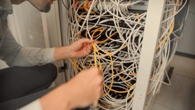 IT technician working with tangled network cables in a server rack. data center maintenance, internet infrastructure, and complex cable management problems in modern technology. digital support repair - Powered by Shutterstock - Get 15% off with code: PIKWIZARD15