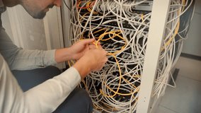 IT technician working with tangled network cables in a server rack. data center maintenance, internet infrastructure, and complex cable management problems in modern technology. digital support repair - Powered by Shutterstock - Get 15% off with code: PIKWIZARD15