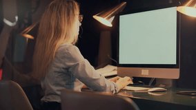 Businesswoman working late at desk in modern office, typing on a computer under warm desk lamp light. Focused and productive atmosphere perfect for remote work, technology, and corporate task complete - Powered by Shutterstock - Get 15% off with code: PIKWIZARD15