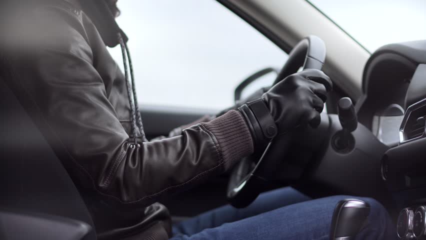 Man in leather jacket and gloves driving a modern car, holding the steering wheel with both hands. Concept of winter driving, road safety, and stylish driver during cold weather.