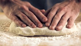hands kneading dough on wooden surface with flour. Homemade baking process in kitchen. Traditional cooking technique for making fresh bread or pastry from scratch. Chef Baking Recipe. Cooking Routine - Powered by Shutterstock - Get 15% off with code: PIKWIZARD15