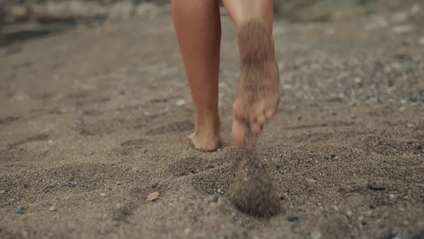 bare feet running on sandy beach. Kicking up sand while walking barefoot by the sea. Concept of freedom, summer, nature connection, and carefree outdoor lifestyle in coastal setting