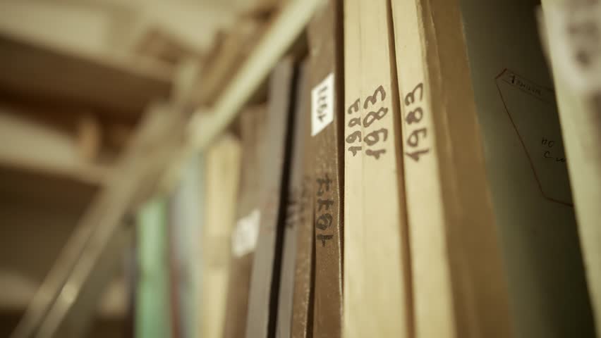 Close-up of old archive folders with handwritten years on spines stored on a shelf. Vintage documents in a dusty archive room, representing history, records, and organized information