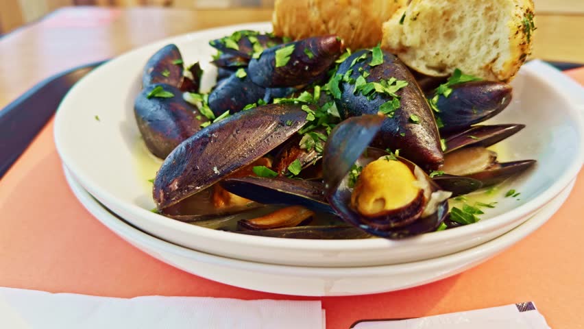 fresh steamed mussels served in a white bowl, garnished with parsley and accompanied by crusty bread. A delicious seafood dish perfect for gourmet. Sea food mussels on dinner. delicious seafood
