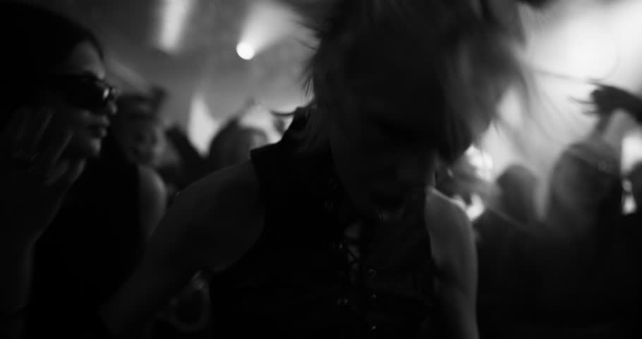 Energetic Woman with Blonde Hair Revels on a Rave Dancefloor, Surrounded by a Lively Crowd Under Pulsating Lights, Capturing the Essence of Nightlife Euphoria. Black and White Slow Motion Footage