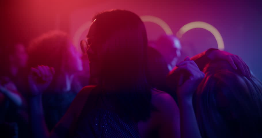 Wild Night Out in a Packed Club. Portrait of a Beautiful Young Asian Female Dancing to Pulsating Electronic Beats Under Vivid Neon Lights. Nightclub Scene Full of Energy and Expression