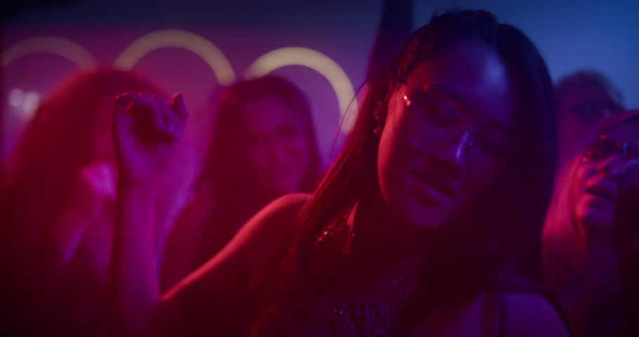 Wild Night Out in a Packed Club. Portrait of a Beautiful Young Asian Female Dancing to Pulsating Electronic Beats Under Vivid Neon Lights. Nightclub Scene Full of Energy and Expression