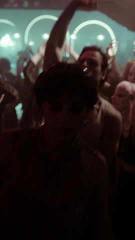 Vertical Screen: Nightclub with Ecstatic People Dancing Under Flashing Neon Lights. Crowd Moves to Electronic Beats in a Packed, Electric Atmosphere. Portrait of a Female Enjoying the Party