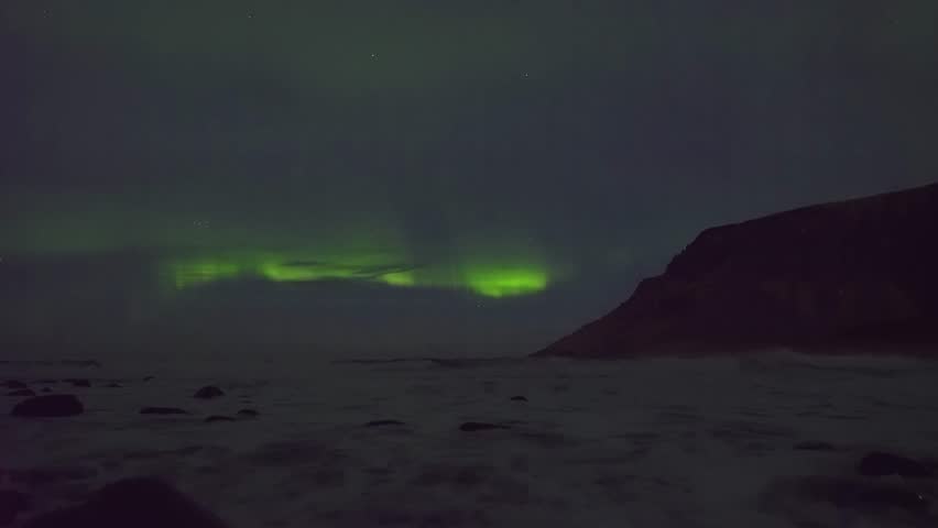 Mesmerizing aurora borealis over rugged Arctic mountains in Norway. Created by solar wind collisions, this rare celestial light show shines bright across the snow.
