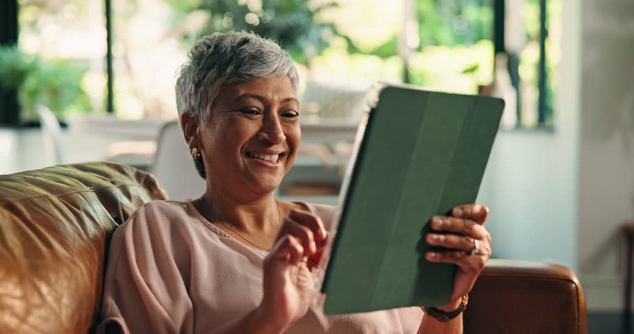 Senior woman, scroll or tablet on sofa for playing puzzle game, gambling app or internet surfing. Retirement, old person or digital tech in home for funny ebook, streaming subscription or online news