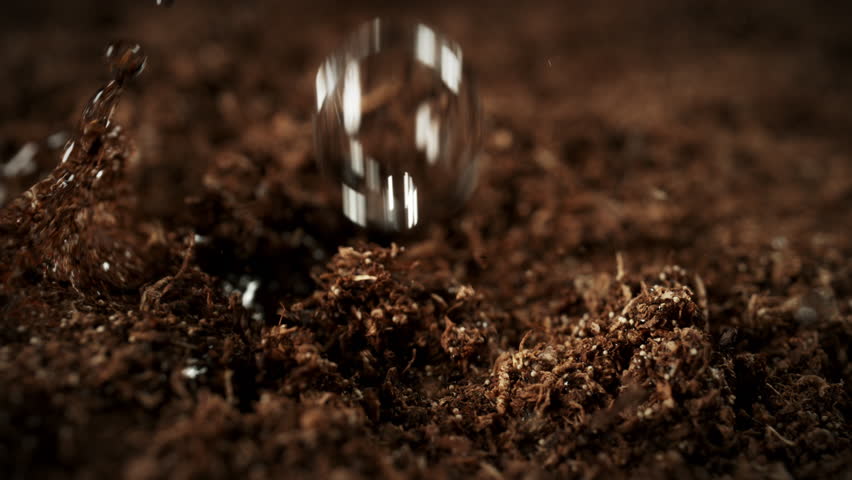 Super Slow Motion Macro Shot of Wated Drops Falling and Splashing on Soil Substrate at 1000fps.
