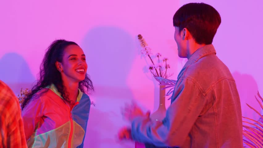 Close up of break dancer team dancing together at modern studio with pink led light. Multicultural people moving to hip hop music while wearing stylish fashion cloth. Crazy, funny mood. Regalement.