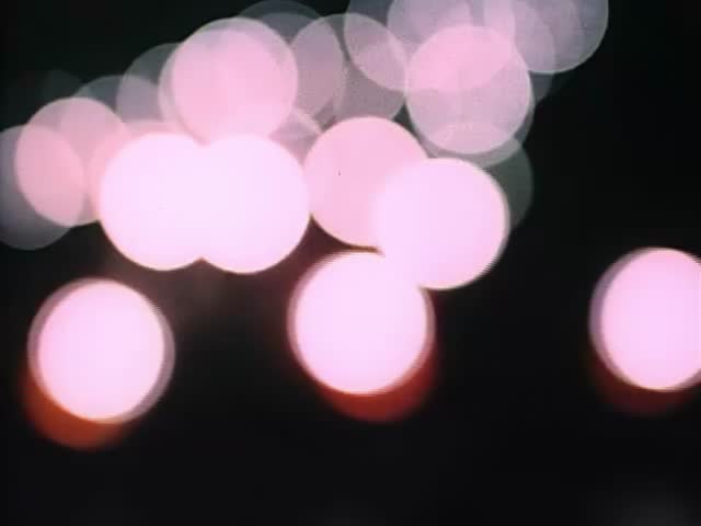 Vintage video of faded bokeh lights on highway at night. Bokeh from car headlights.