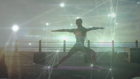 Woman unfurling yoga mat seaside dawn holding warrior II pose as glowing mesh pulsing for wellness. Fitness, meditation, mindfulness, serenity, energy, balance, landscape - Powered by Shutterstock - Get 15% off with code: PIKWIZARD15