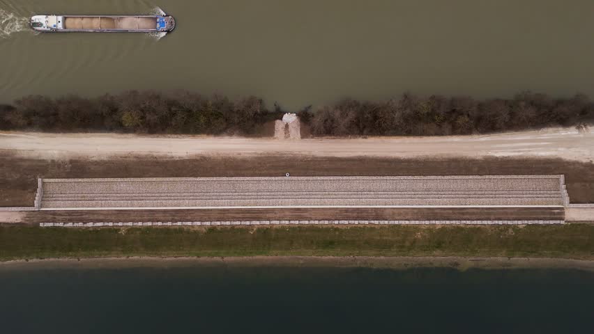 Aerial view of serene seine retention basin with a barge on the seine river surrounded by lush trees, Chatenay sur Seine, France.