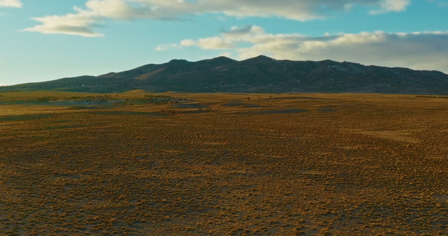 Drone shot of Nevada high desert at sunset. Camera slowly flies toward mountains