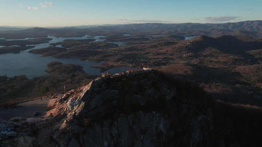 An epic sunset aerial over Bell Knob lookout, a popular hiking location for panoramic views, with a vast landscape of finger lakes around Lake Chatuge in the north Georgia mountains near Hiawassee.