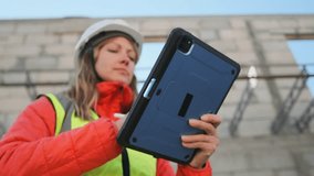 A construction engineer in a hard hat and safety vest stands near an unfinished building, using a tablet. With focused attention, she reviews project documentation and makes adjustments with a stylus. - Powered by Shutterstock - Get 15% off with code: PIKWIZARD15