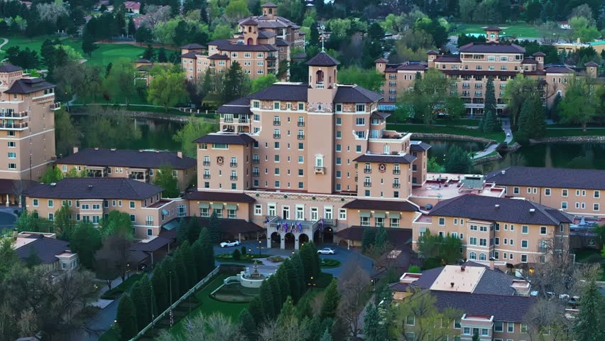 Aerial pan of Broadmoor entrance surrounded by lush greenery and scenic mountain backdrop