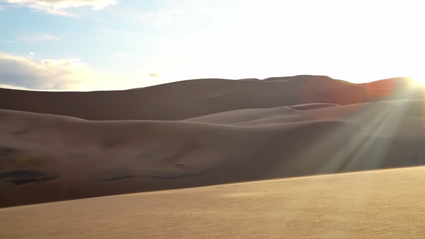 Warm evening light casts long shadows on smooth sand ridges in Great Sand Dunes National Park, natural backdrop background, no people