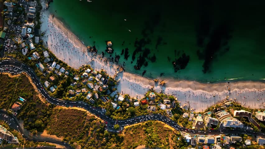 Aerial view of coastal houses and traffic along a beautiful sandy beach and ocean, Cape Town, Western Cape, South Africa.